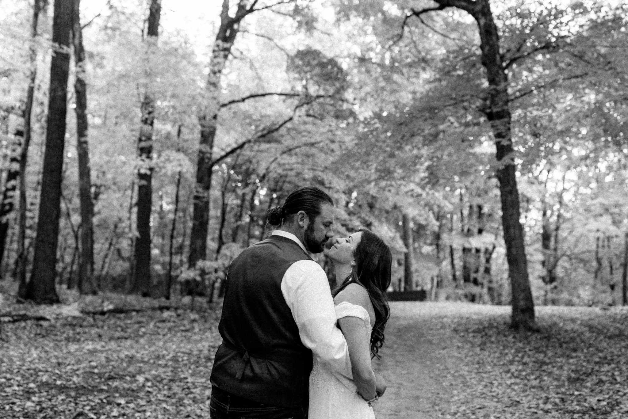 Bride and groom share an embrace in the woods.
