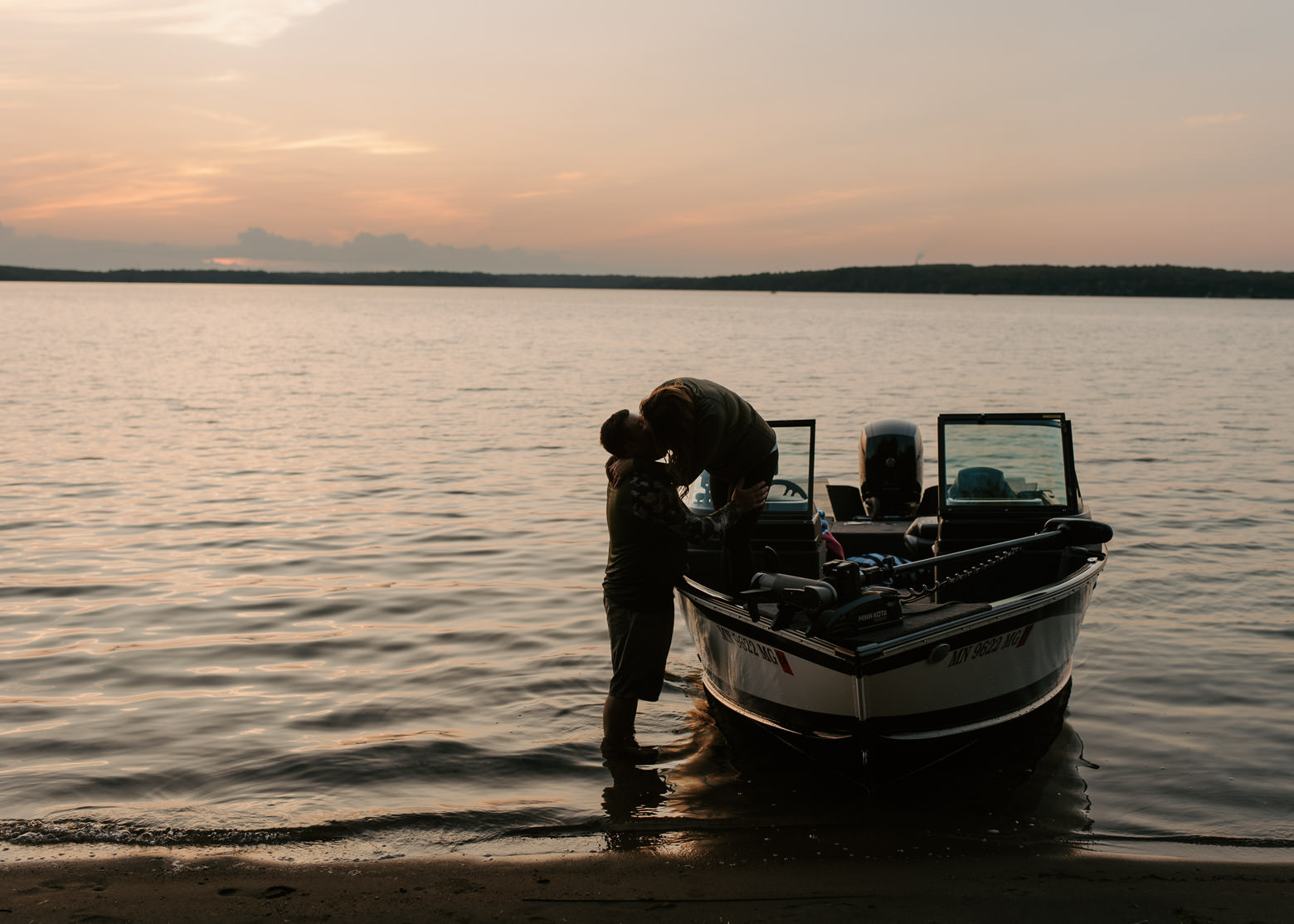 A couple kissing on a boat at sunset near Grand Rapids, Minnesota.